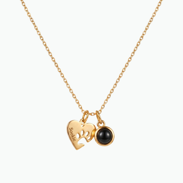 Gold necklace with a heart-shaped pendant and black bead on a white background